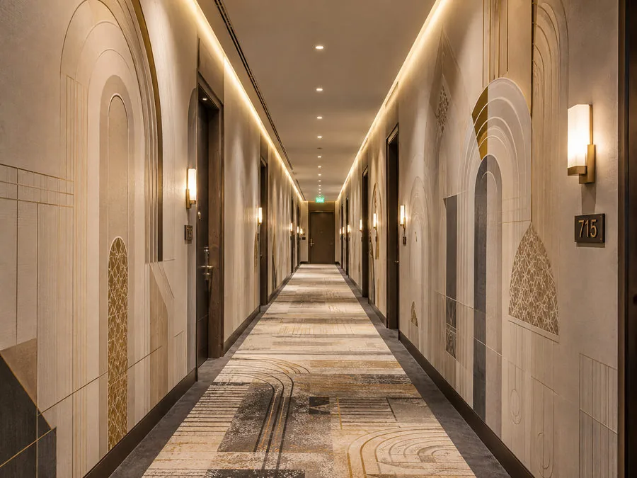 Hotel corridor with walls printed in cream and gold art deco arch patterns, brass sconces and a room number plaque